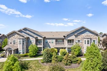 The exterior of an apartment building at Stonepost Crossing, with private fenced-in balconies overlooking a beautiful, lush green landscape.